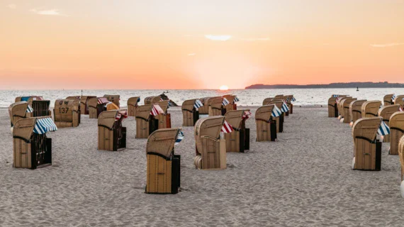 Gruppo di sedie su una spiaggia con cielo nuvoloso.