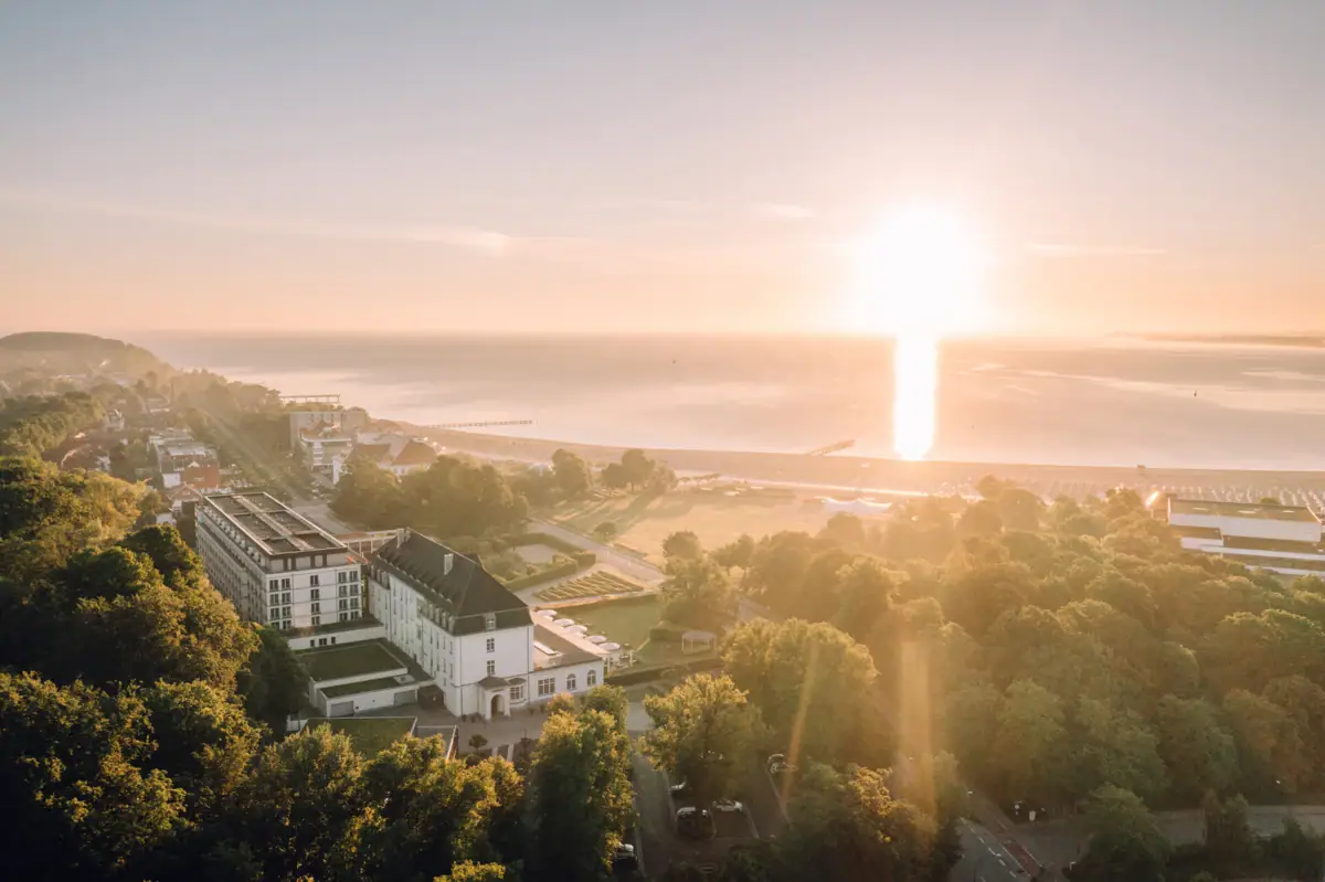 Eine Stadt mit Bäumen und einem Gewässer bei Sonnenaufgang.