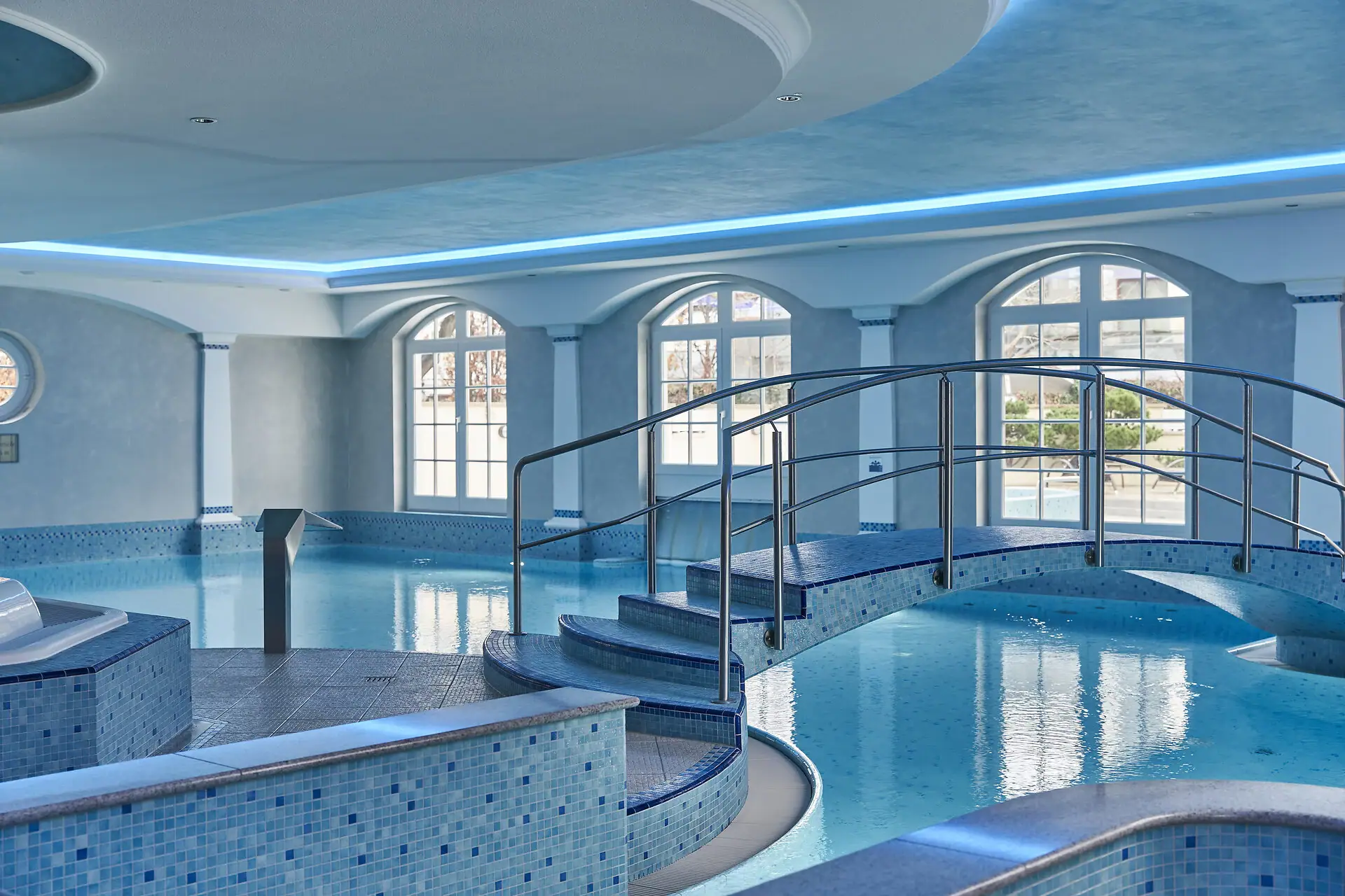 Poollandschaft zum Treiben lassen. Bcklick in einen blau gefliesten Poolbereich, Brücke über die Wasseroberfläche