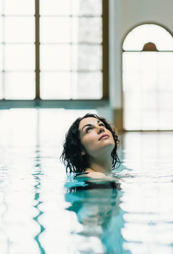 Donna in piscina al chiuso che guarda verso l'alto.