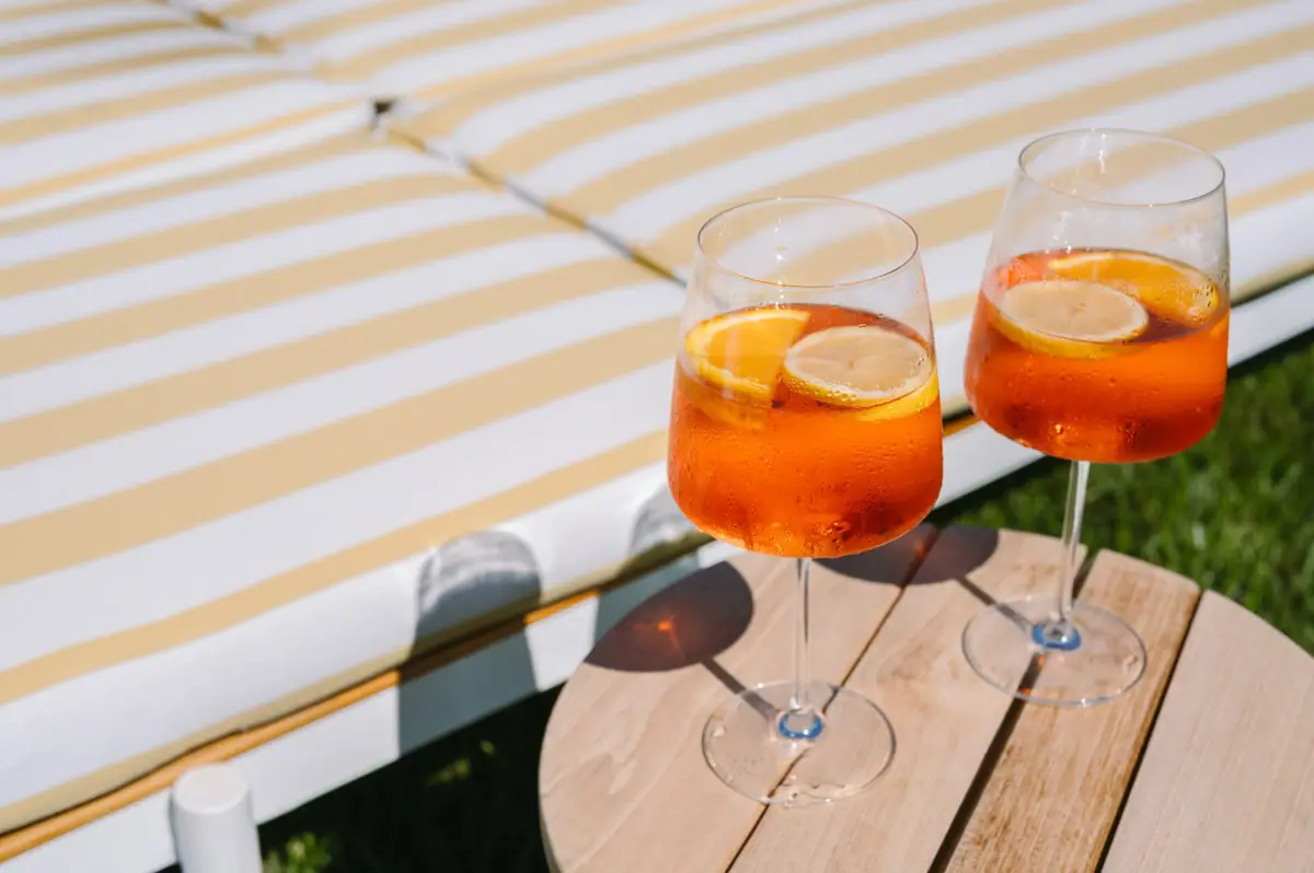 Aperol Spritz Due bicchieri con un liquido arancione e fette di limone su un tavolo.