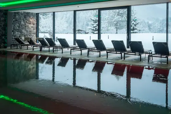 Piscina coperta Una piscina con delle sedie davanti a una grande finestra.
