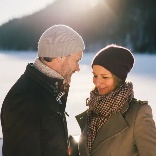 Uomo e donna in piedi sulla neve, indossano giacche e berretti.