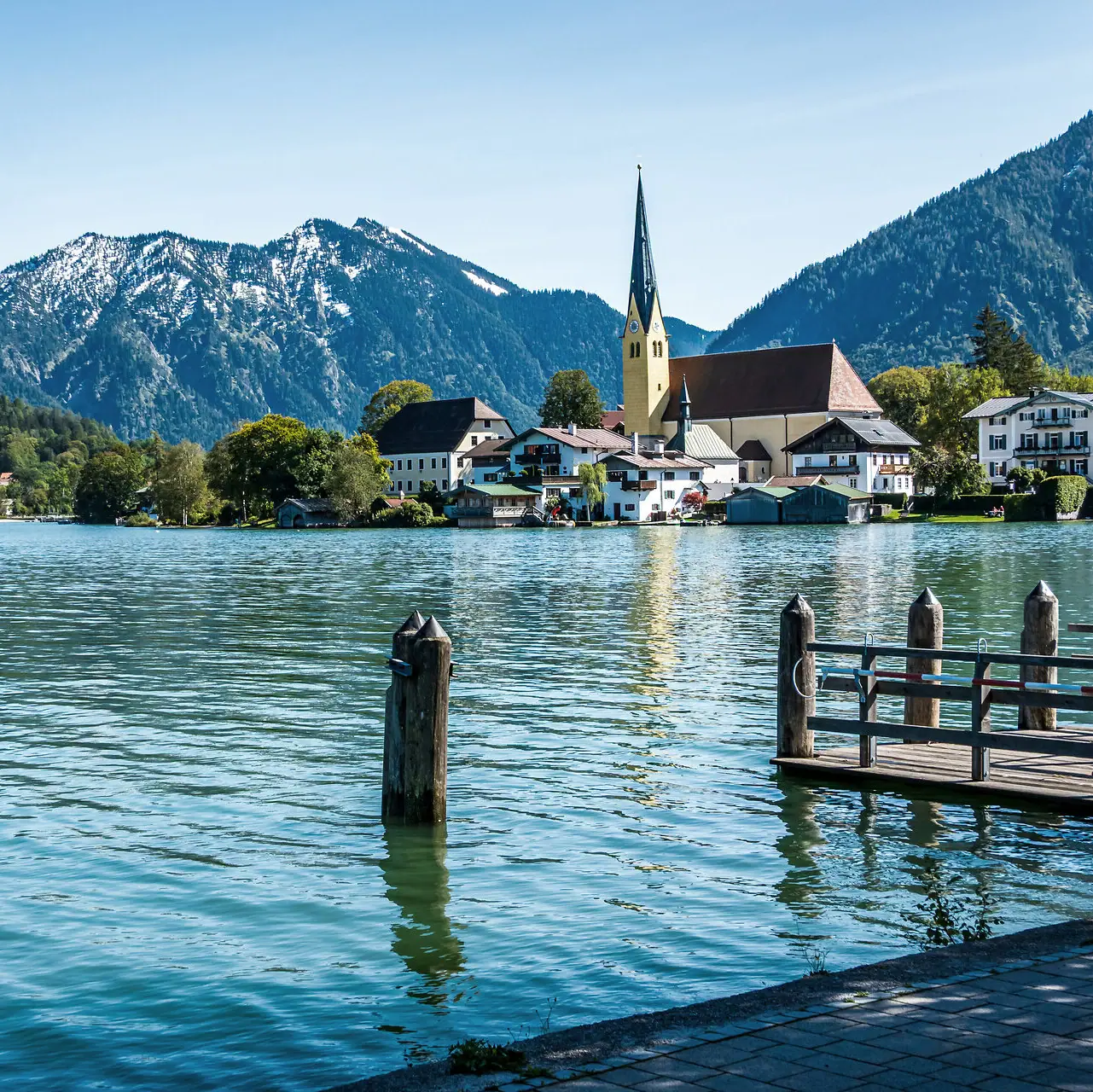 Un lago con una chiesa e le montagne sullo sfondo.