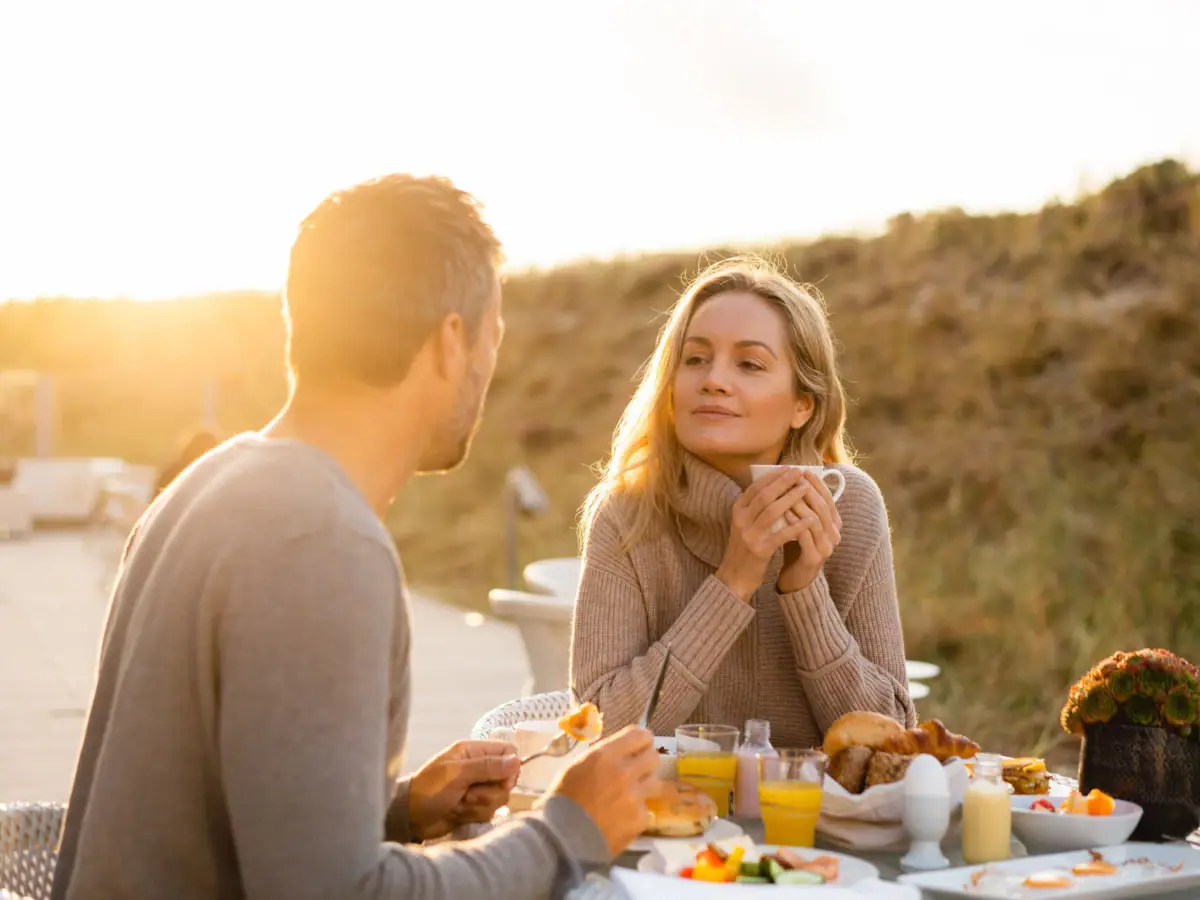 Sylt Un uomo e una donna seduti a un tavolo con del cibo.