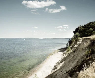 Spiaggia con un corpo d'acqua e una scogliera sabbiosa.