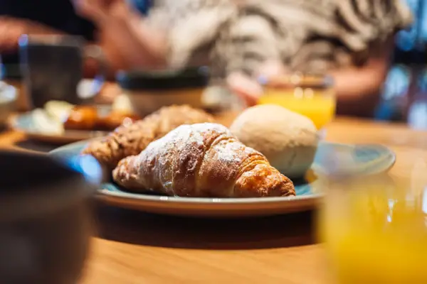 Piatto di cibo su un tavolo con croissant e bevanda.