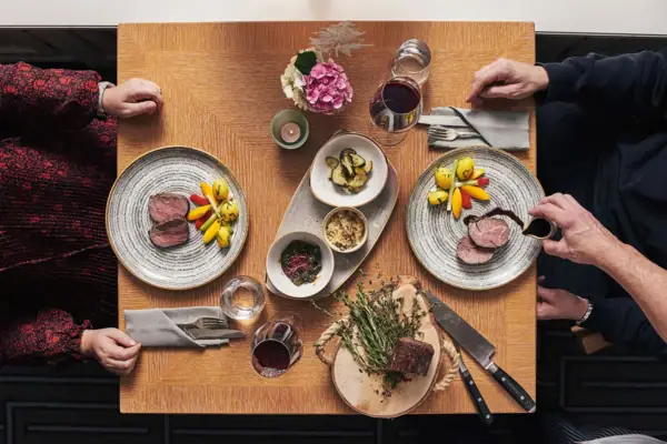 Eine Gruppe von Menschen sitzt an einem Tisch mit Tellern voller Essen.