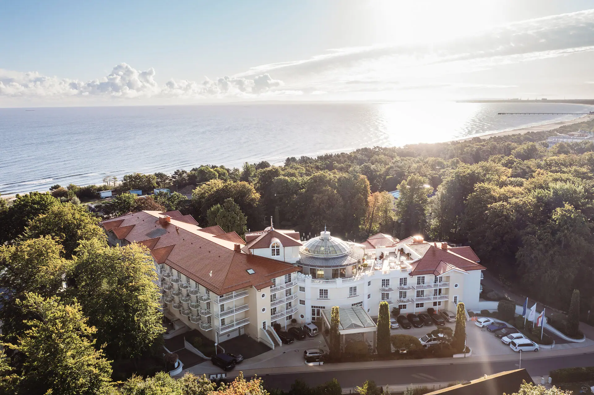 Großes Gebäude mit Bäumen und einem Gewässer im Vordergrund.