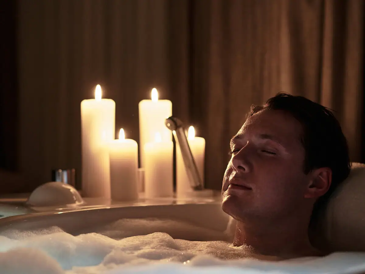 Ein Mann in einer Badewanne mit Kerzen.