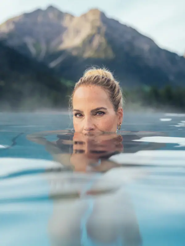 Una donna nella piscina all'aperto dell'A-ROSA Ifen Hotel Kleinwalsertal