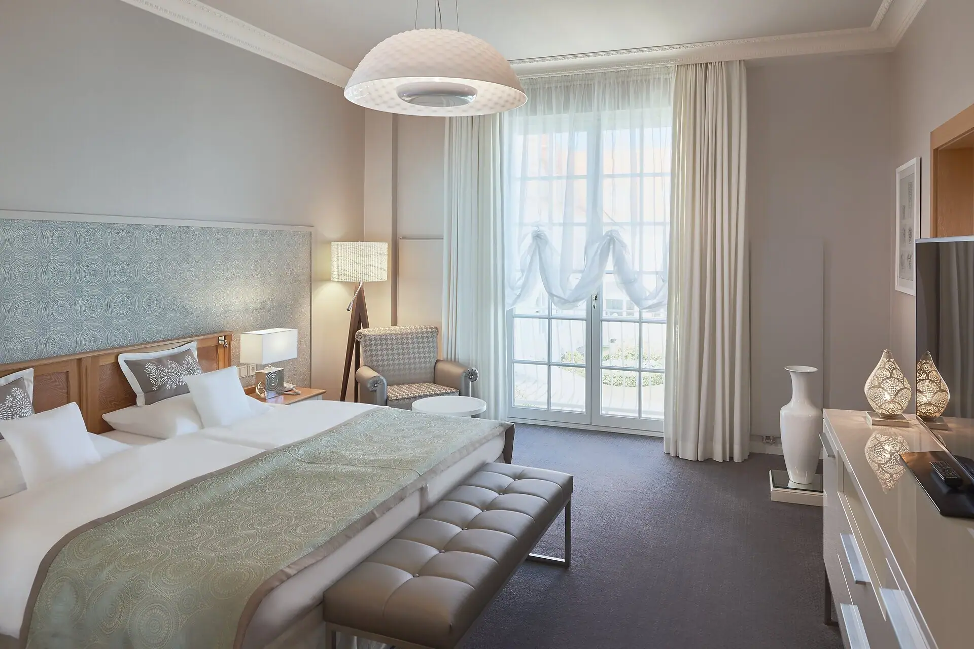 Zimmer Kurhaus Binz Ein Hotelzimmer mit einem Bett und einer Bank.