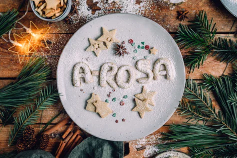 Piatto con biscotti su sfondo natalizio con albero e decorazioni.