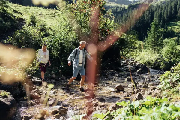 Un uomo e una donna camminano in equilibrio sulle pietre di un ruscello.