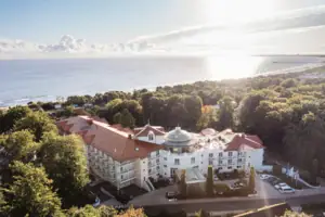 Grande edificio con alberi e specchio d'acqua in primo piano.