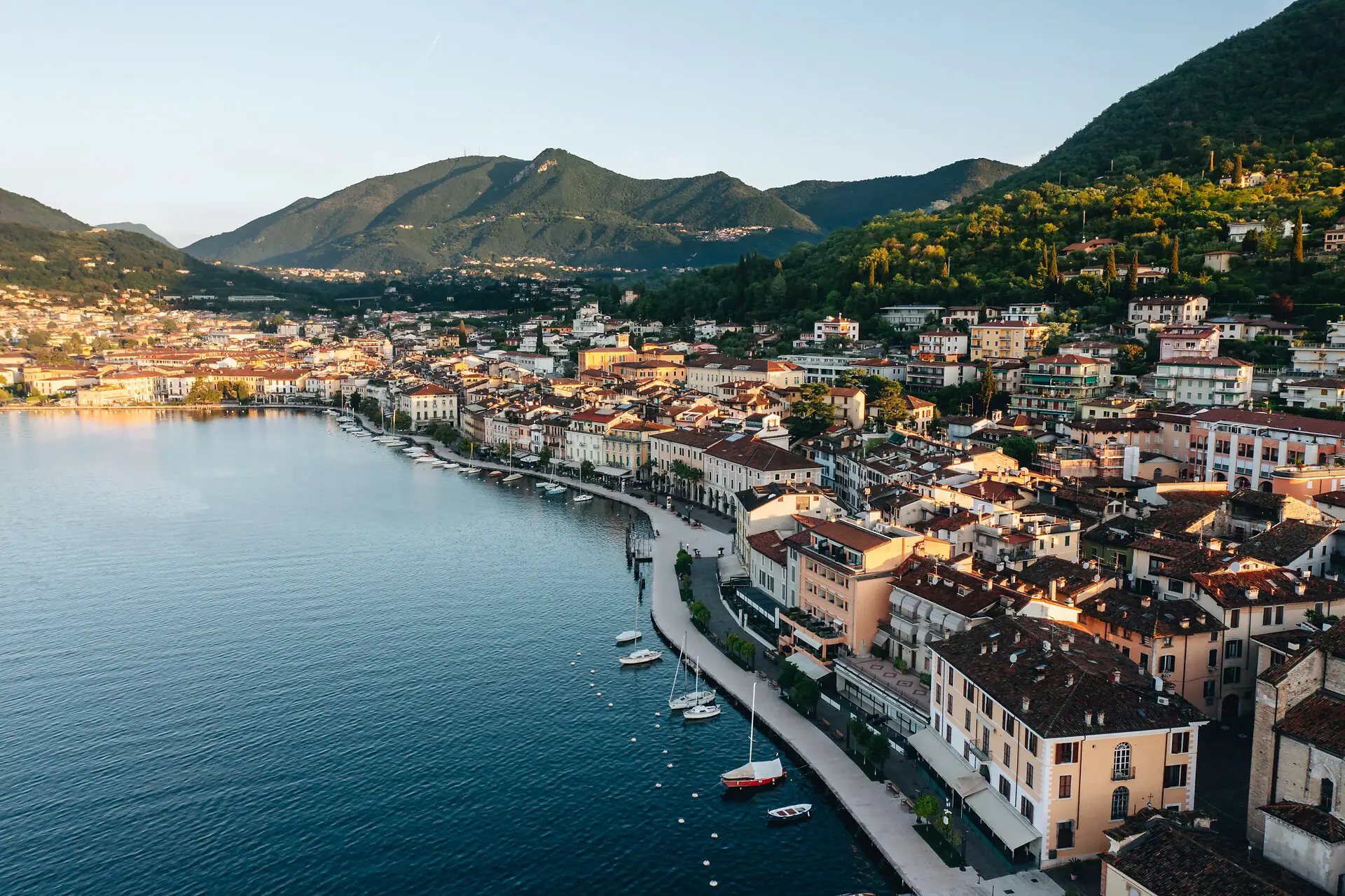 Gardaseeufer Città costiera accanto a un corpo d'acqua con montagne sullo sfondo.