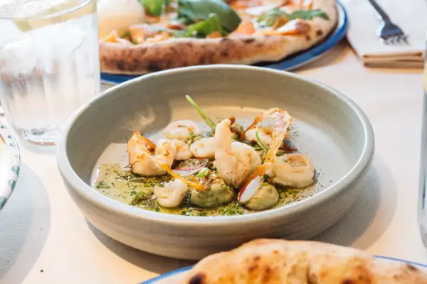 Ein Teller mit Scampi hünsch angerichtet, auf einem Tisch mit anderen Speisen.