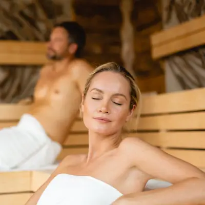sauna e relax Una donna seduta in una sauna, un uomo sullo sfondo.
