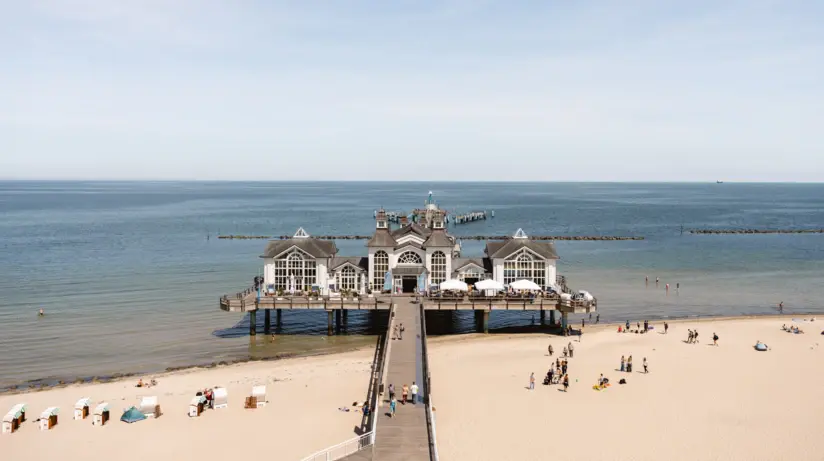 Spiaggia con edificio sull'acqua, circondata da aria limpida e nuvole leggere.