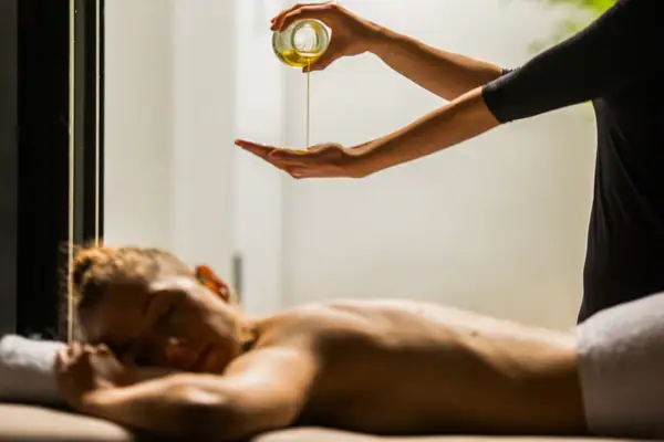 Eine Person gießt Öl in die Hand einer anderen Person.