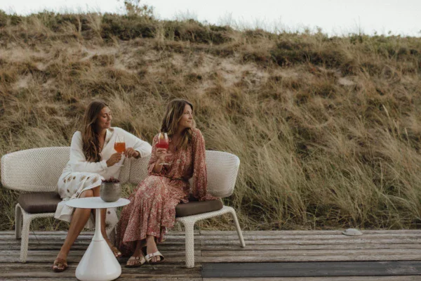 Due donne sedute su una panchina all'aperto, una delle quali indossa un abito da sposa.