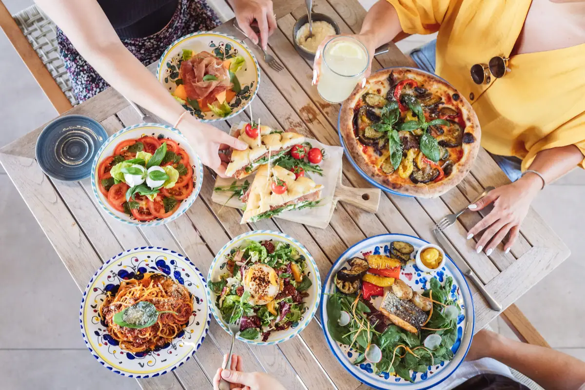 Un gruppo di persone sta mangiando insieme a un tavolo.