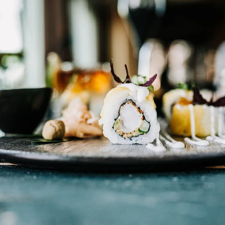 Piatto di sushi con salsa su un tavolo.