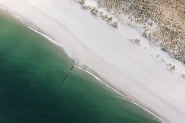 Una bella spiaggia di Sylt con sabbia e acqua vista dall'alto.