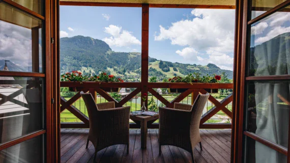 Balcone con sedie e un tavolo, vista su montagne e cielo nuvoloso.