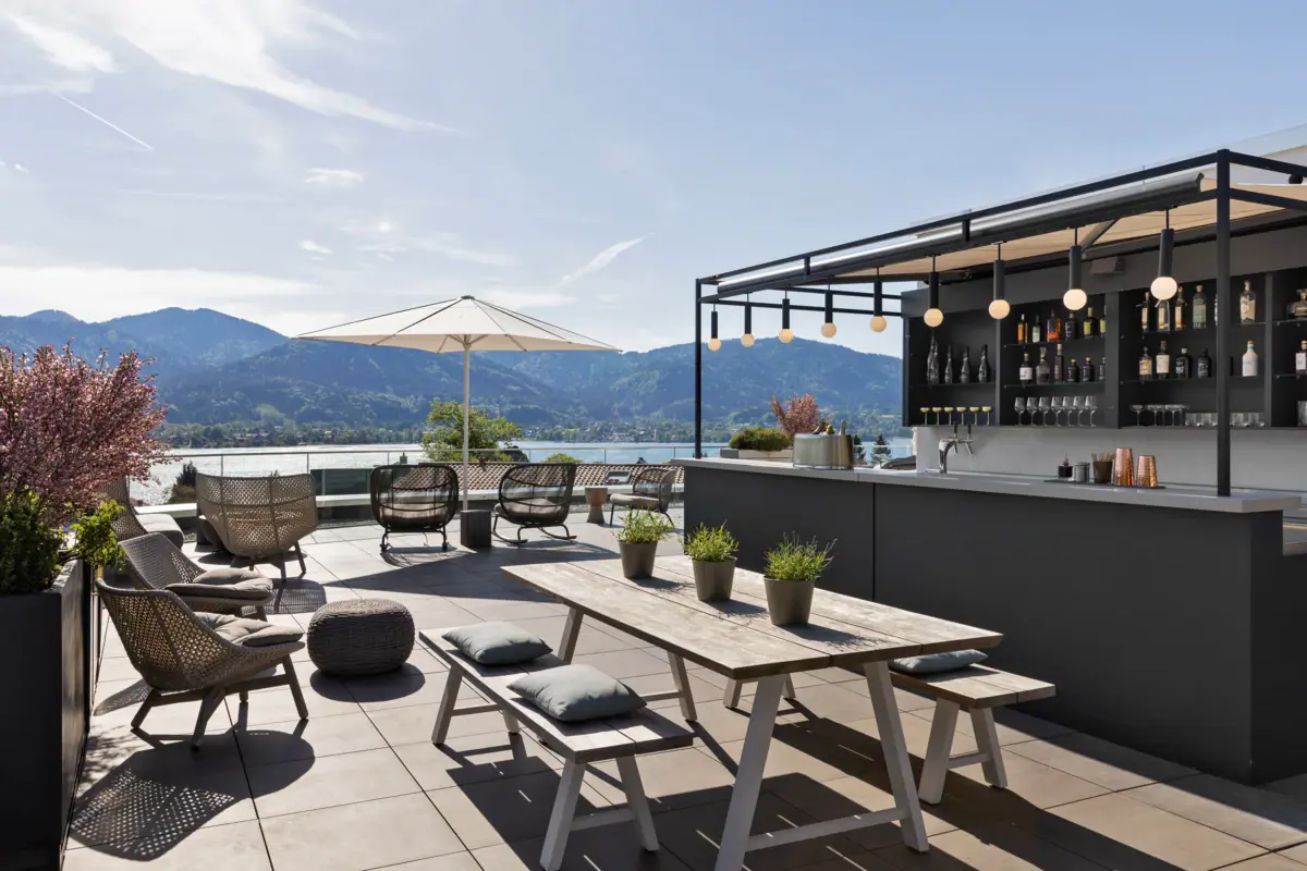 Terrazza sul tetto con bar, sedie, tavolo e ombrellone.