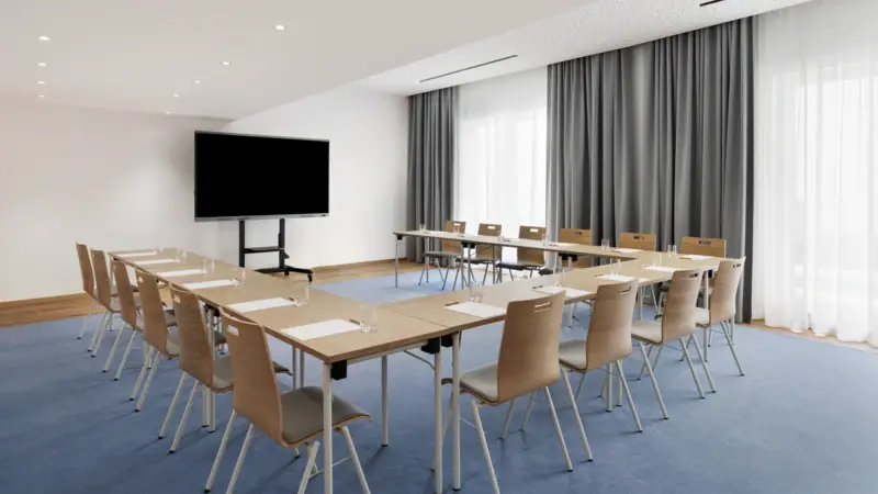 Convegno nella sala conferenze di Tegernsee L'A-ROSA Tegernsee come hotel per congressi, dotato di una sala conferenze con alcuni tavoli e sedie.