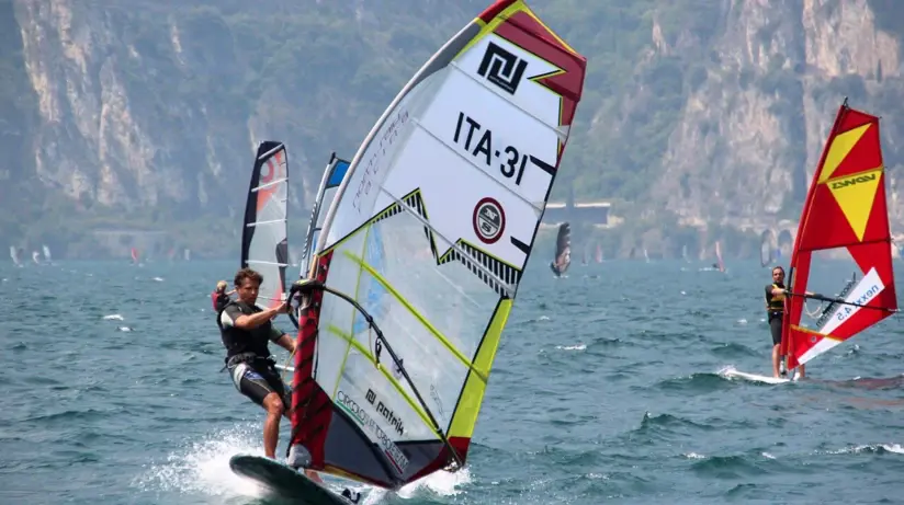 Un uomo su una tavola da windsurf sul lago di Garda.