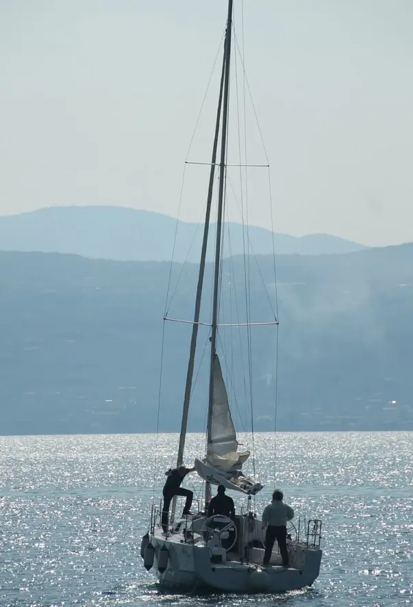 Tre persone in barca a vela sull'acqua.