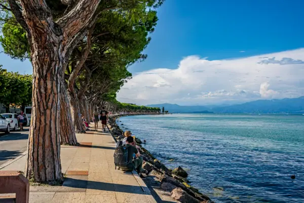Peschiera del Garda Un gruppo di persone è seduto sulla riva di uno specchio d'acqua.