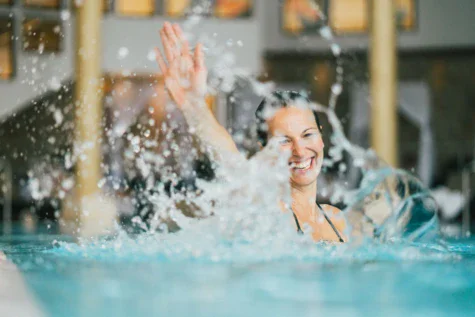 Donna che nuota in piscina con schizzi d'acqua.