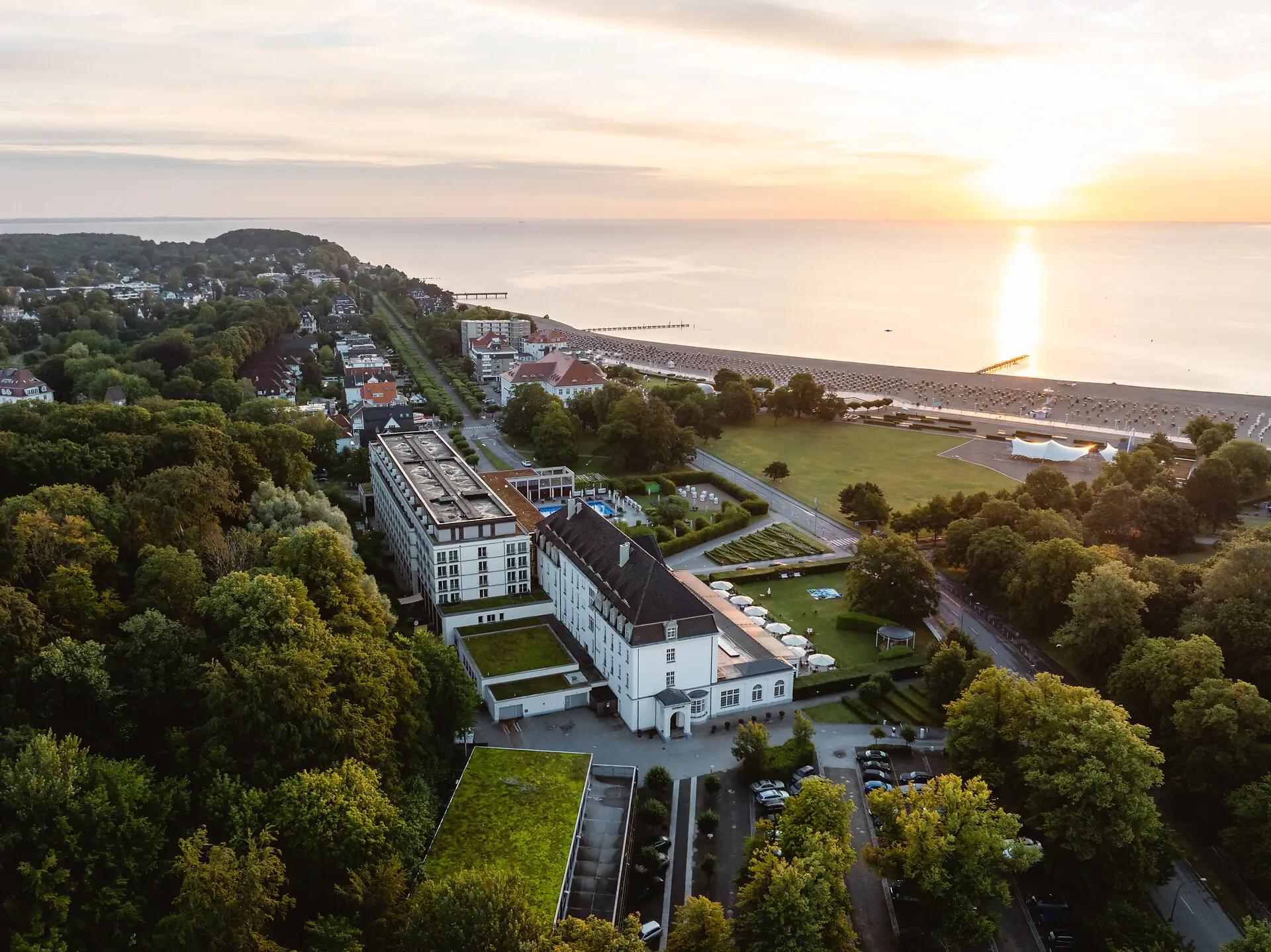 Luftaufnahme einer Stadt mit Bäumen und einem Gewässer.