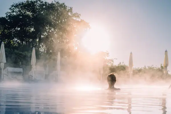 Eine Person in einem dampfenden Außenpool.