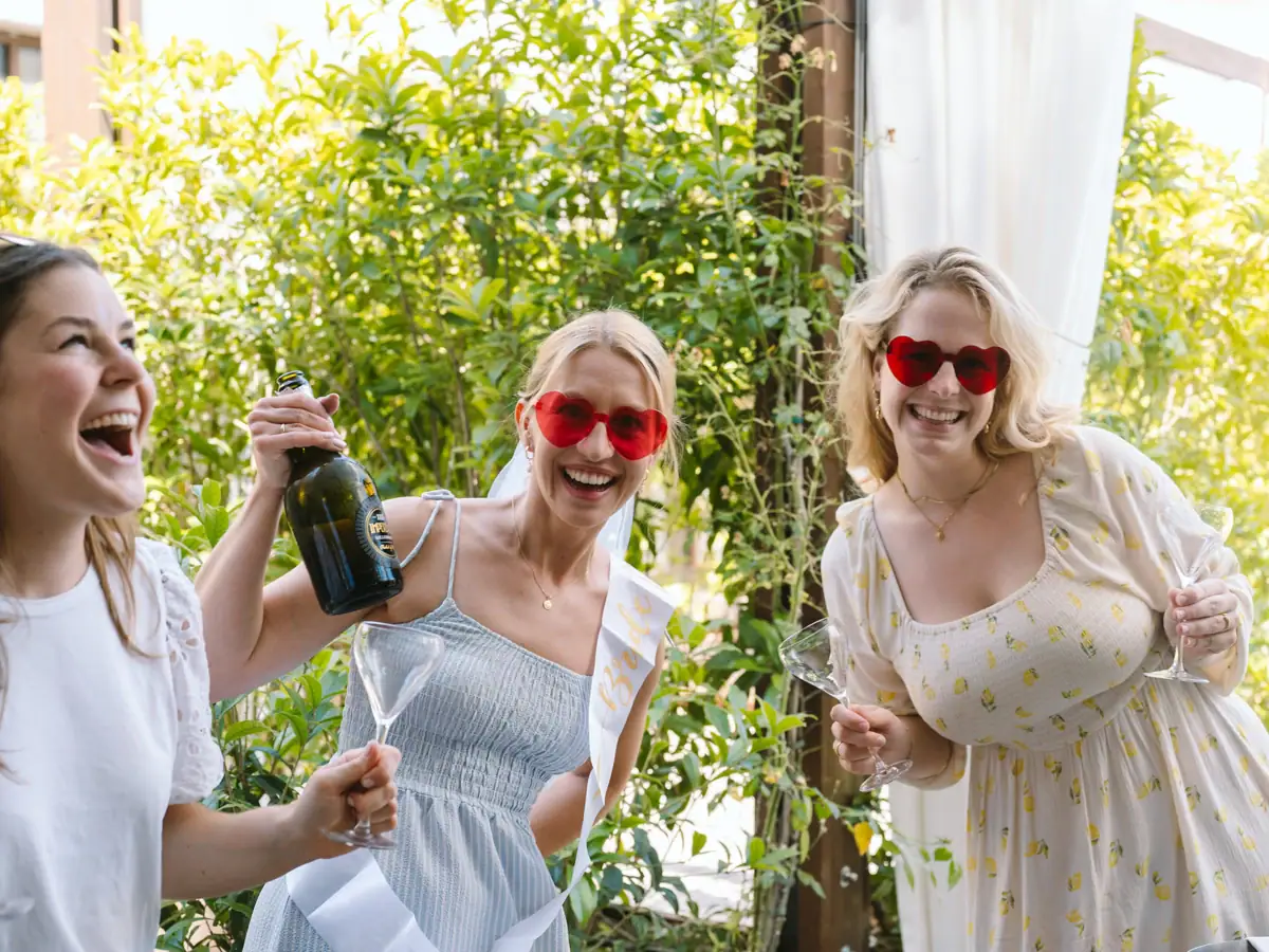 Freundinnen lachen und feiern mit Prosecco bei einer Bachelorette-Party am Gardasee