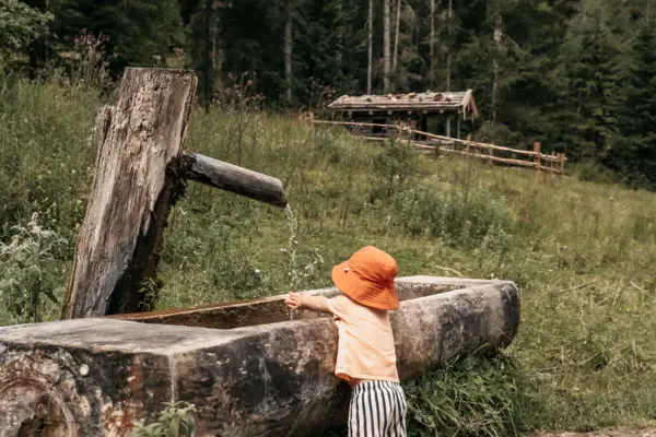 Un bambino beve da una fontanella all'aperto.