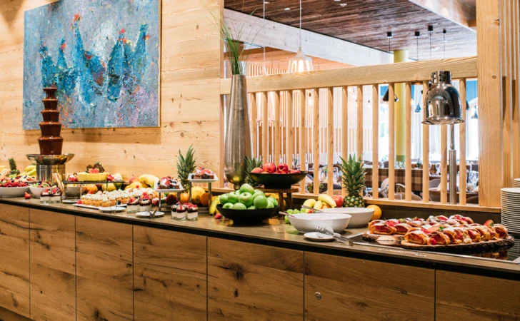 Buffet con varietà di cibi disposti su un bancone in un ambiente interno.