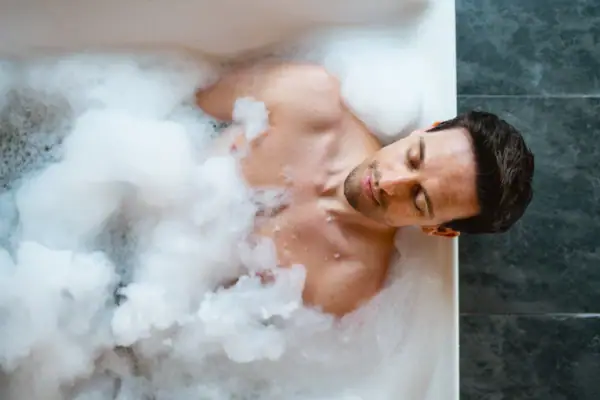 Ein Mann liegt in einer Badewanne mit Schaum.