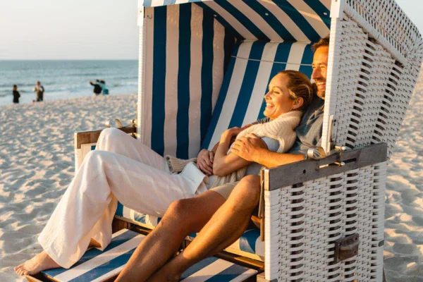 Uomo e donna seduti su una sdraio in spiaggia.