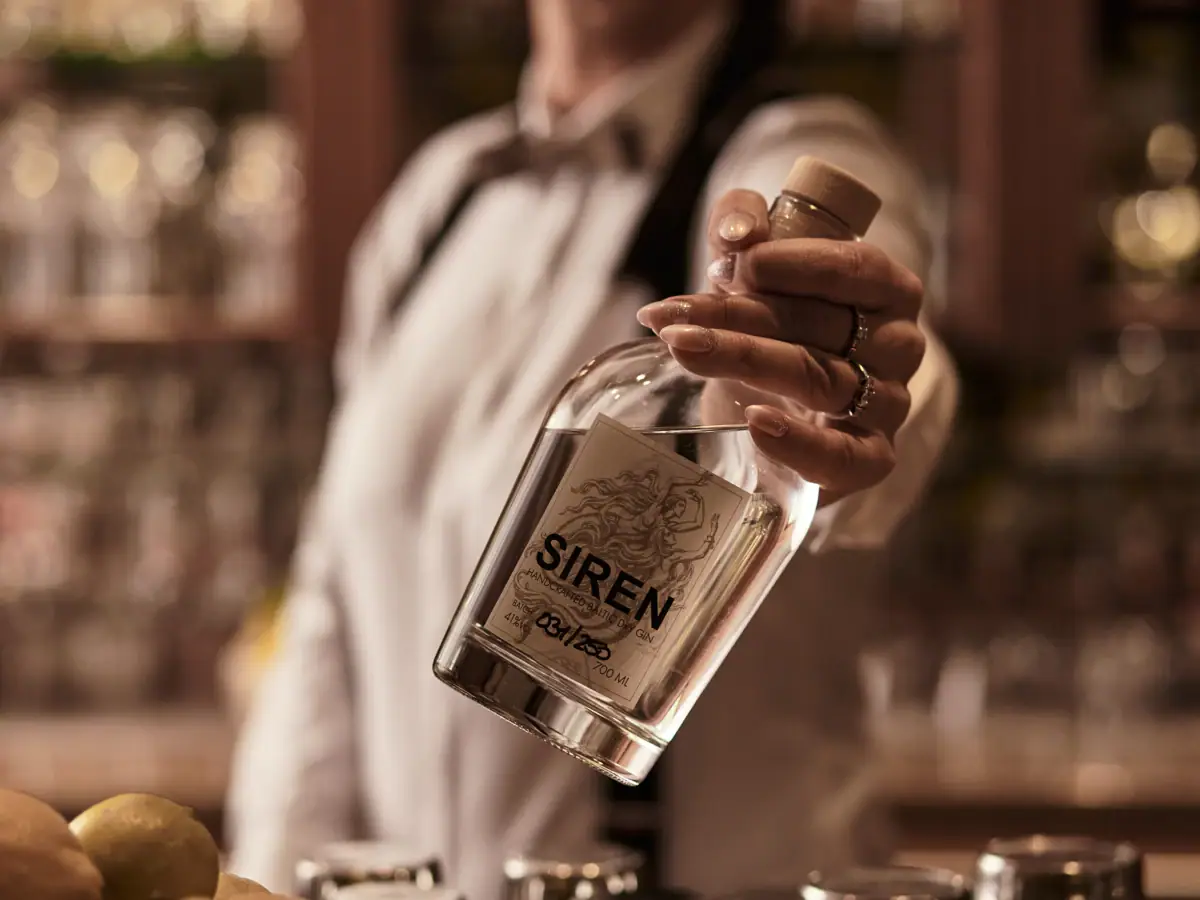 Eine Person hält eine Flasche Alkohol.