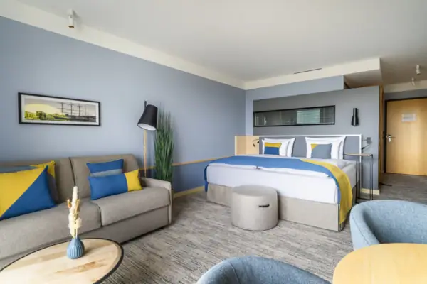 Zimmer A-ROSA Travemünde Ein modernes Hotelzimmer mit einem großen Bett und Couch.