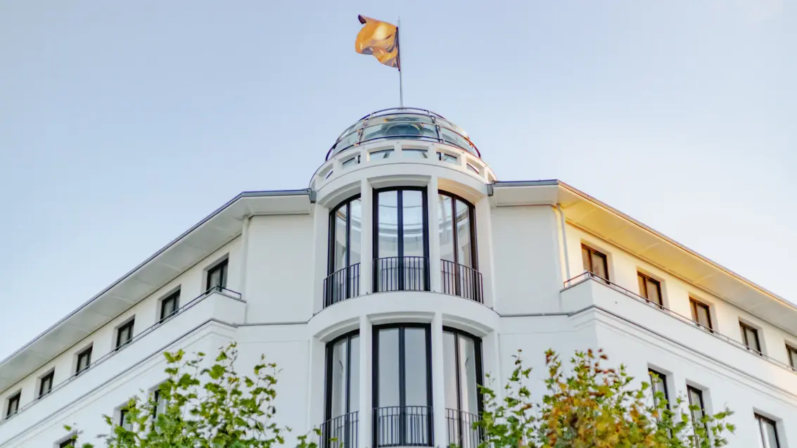 Una bandiera su una cupola di vetro di un edificio bianco è illuminata dal sole e soffia nel vento.