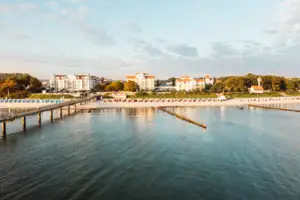 Ein Gewässer mit einem Steg und Gebäuden im Hintergrund.