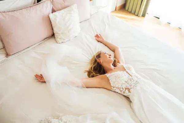 Eine Frau liegt auf einem Bett in ihrem Hochzeitskleid.