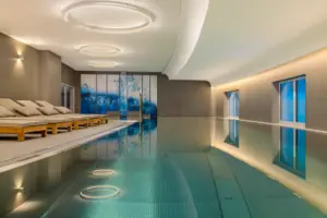 La piscina coperta dell’A-ROSA Hotel Tegernsee con sedie a sdraio lungo il bordo.