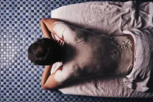 Una persona è sdraiata su un asciugamano con un involucro bianco per il corpo.