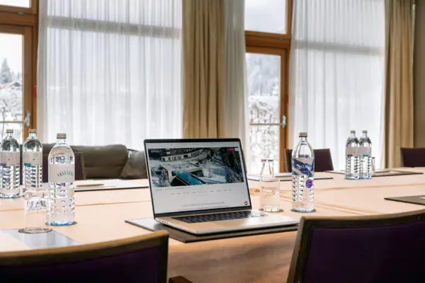 Laptop auf einem Tisch mit Wasserflaschen und einem Fenster im Hintergrund